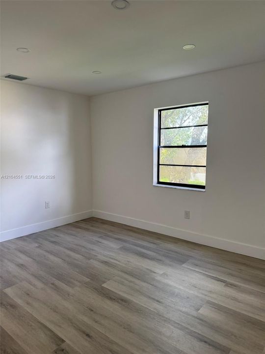 Neutral-toned walls, wood-finish flooring, and a single-hung window with dark-toned framing