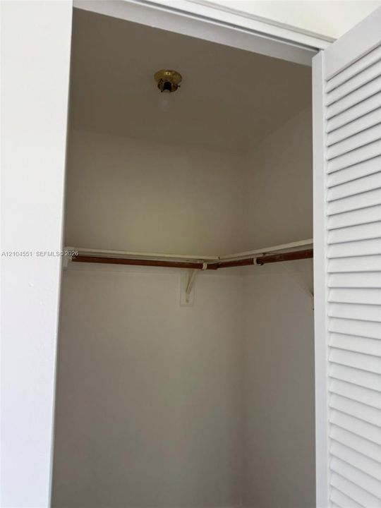 Closet featuring louvered bi-fold doors, interior lighting, and built-in shelving with a hanging rod