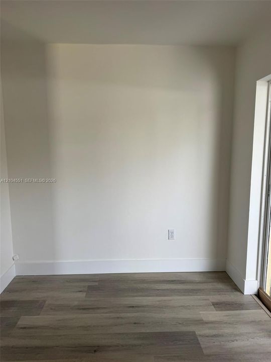 Neutral interior space featuring wood-finish flooring and light-toned wall surfaces