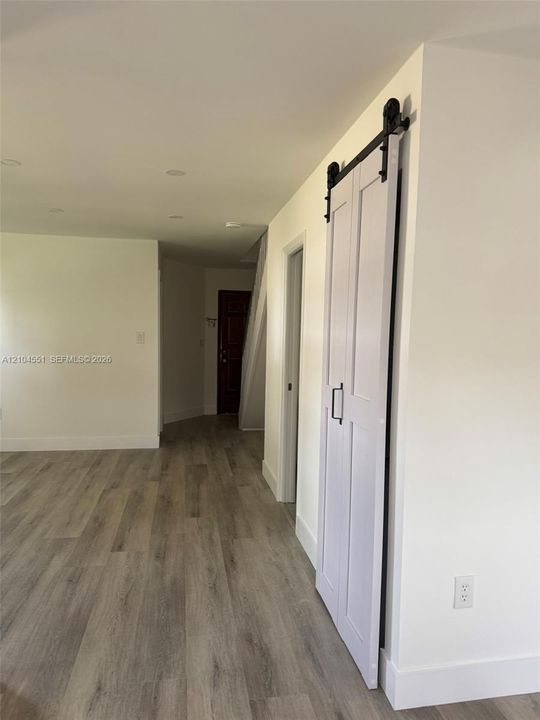 Interior space featuring wood-finish flooring, recessed lighting, and a white paneled sliding barn door with matte black hardware