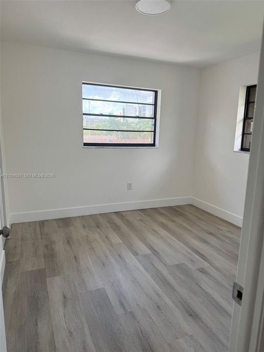 Neutral-toned wood-finish flooring, crisp white walls, and horizontal-pane windows with dark frames