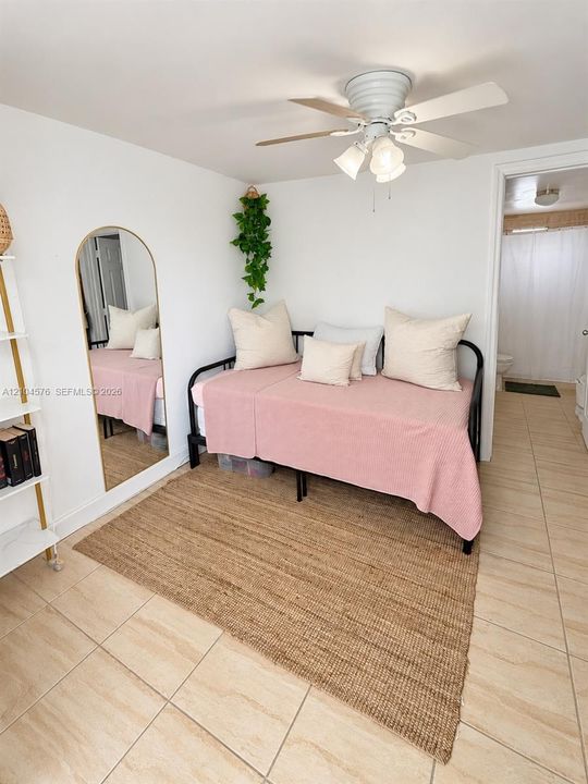 Neutral-toned ceramic tile flooring, white-painted walls, and a ceiling-mounted light fixture with a multi-blade fan