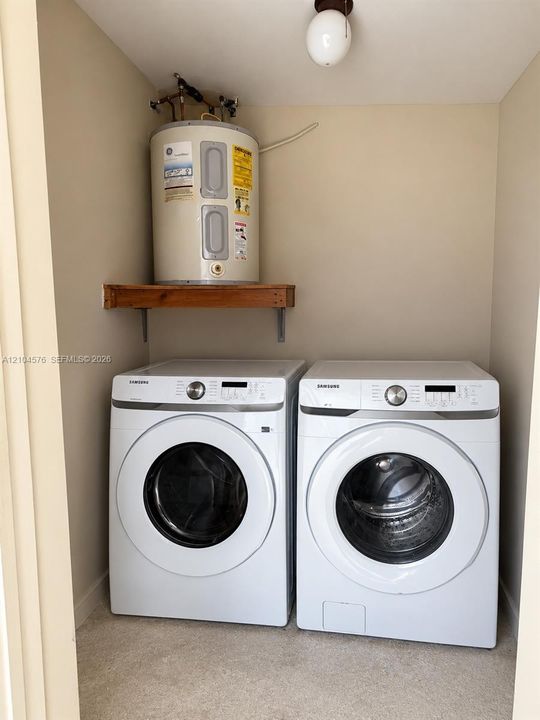 Dedicated laundry area featuring a wall-mounted wood shelf and globe-style ceiling lighting