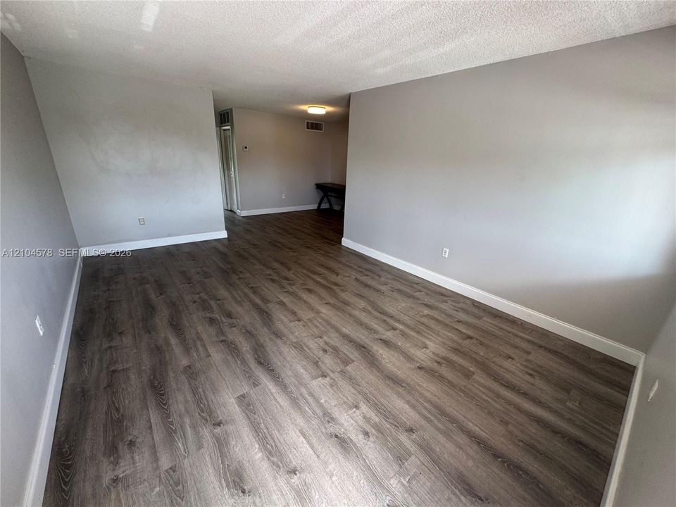 Wood-finish flooring throughout, stainless steel refrigerator, white cabinetry, and exterior door with glass insert