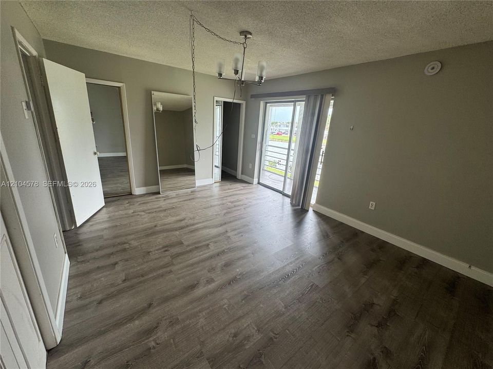 Interior space featuring wood-finish flooring, a full-length wall mirror, a hanging light fixture, and a sliding glass door providing external access