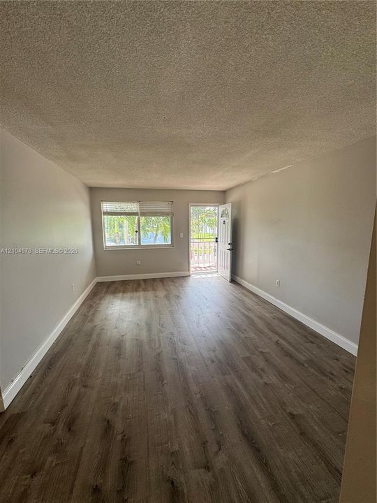 Interior space featuring wood-finish flooring, neutral wall paint, and natural light from a window and door