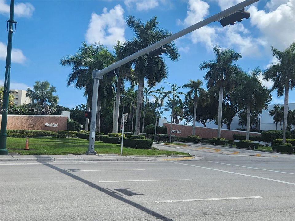 Brick perimeter wall with signage, manicured landscaping, and mature palm trees