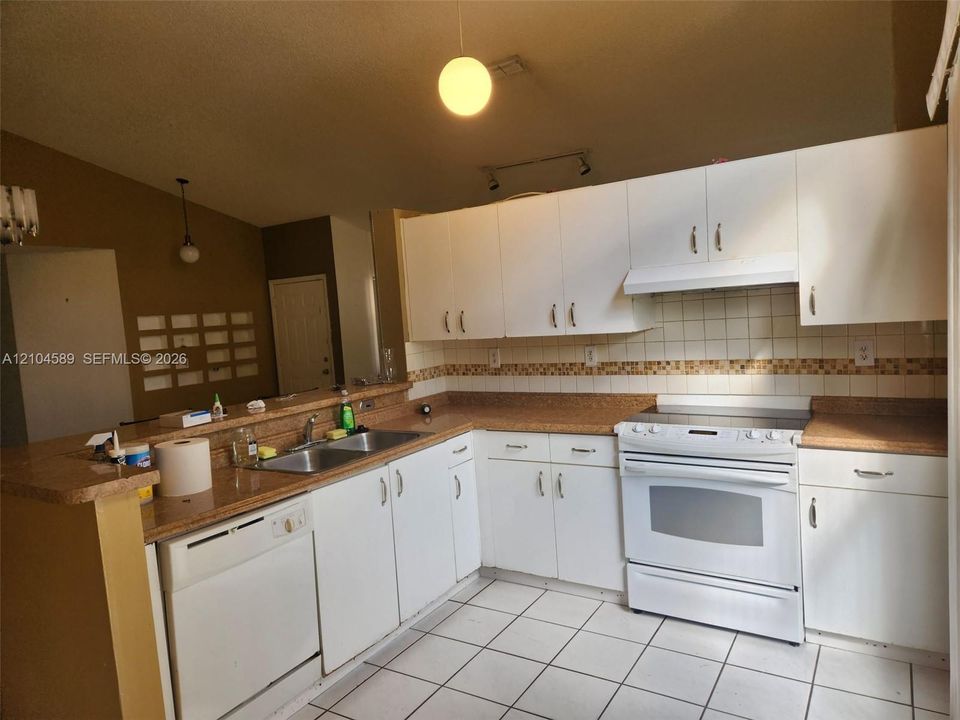 Vaulted ceiling with a ceiling fan, arched window, tile flooring, built-in cabinetry, and a countertop breakfast bar