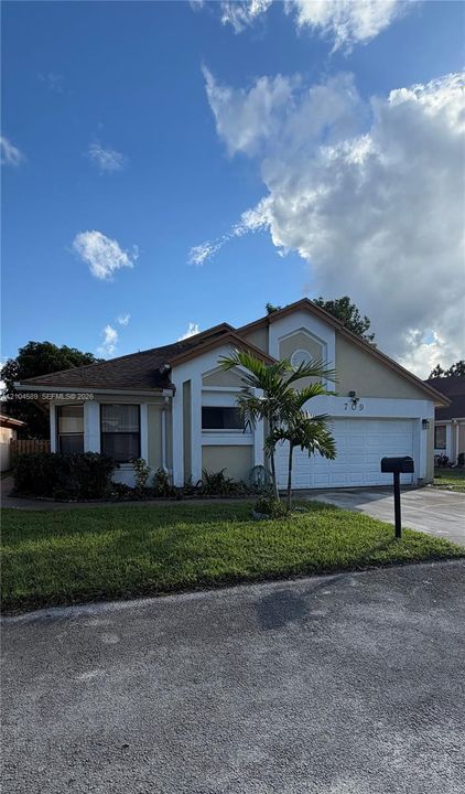 Single-story exterior featuring a stucco facade, front-facing garage, decorative gable trim, and a concrete driveway