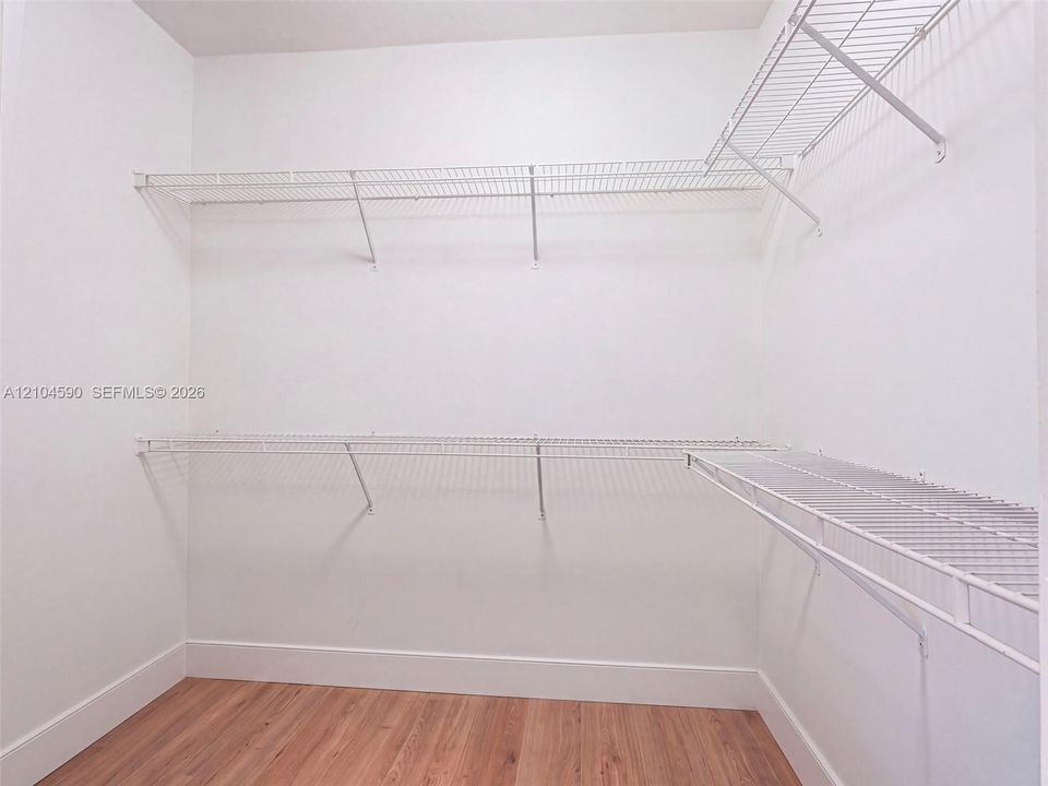 Walk-in closet featuring wood-finish flooring and tiered white wire shelving