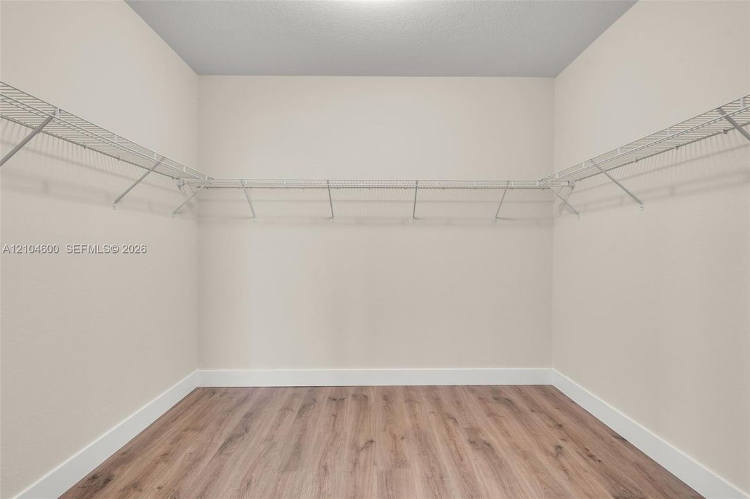 Storage space featuring wood-finish flooring and wall-mounted wire shelving units