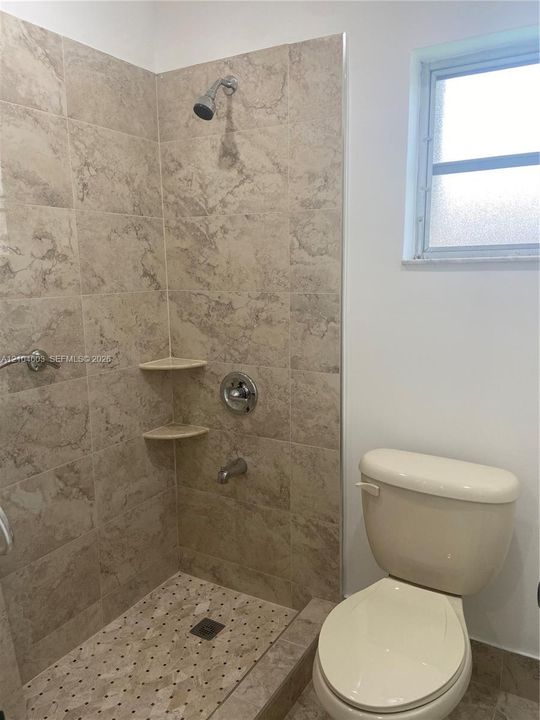 Shower with full tile surround, two built-in corner shelves, and a tiled shower floor