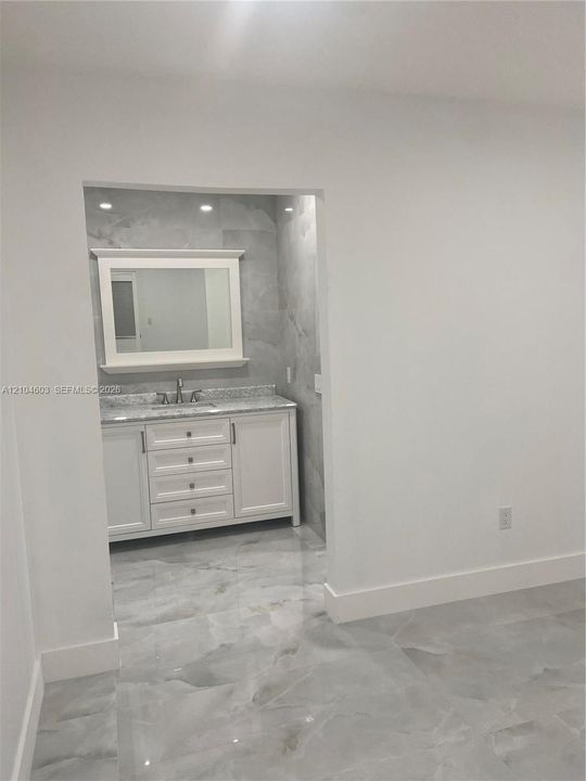Vanity with a light-toned countertop, integrated sink, and white cabinetry