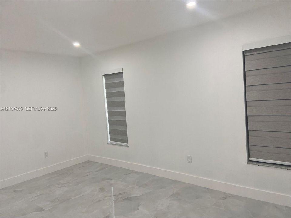 Recessed lighting, light-toned walls, and grey-toned tile flooring