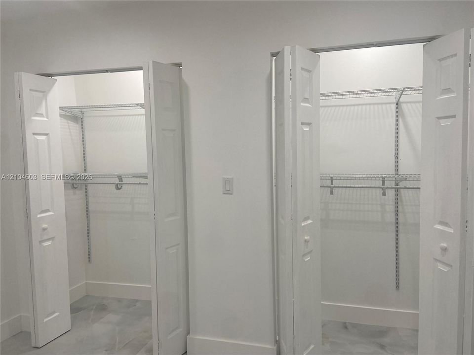 Dual closets featuring bi-fold panel doors and adjustable wire shelving systems