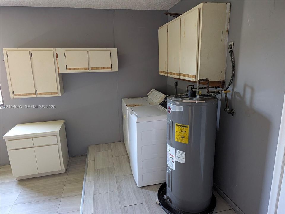 Utility space featuring light-toned cabinetry, neutral wall-finish, and tile flooring
