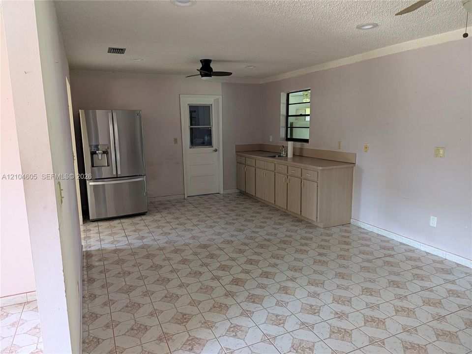 Kitchen area featuring patterned ceramic tile flooring, neutral cabinetry, a stainless steel French-door refrigerator, and a recessed ceiling fan