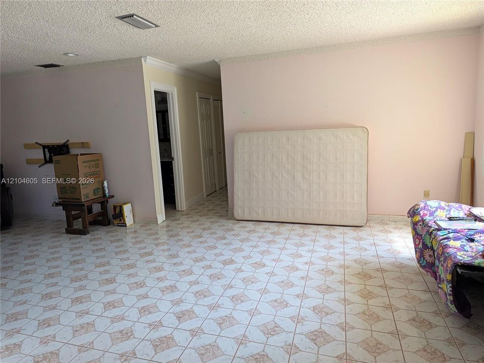 Interior space featuring tile flooring with a geometric pattern, textured ceiling finish, and dual door access to a secondary space