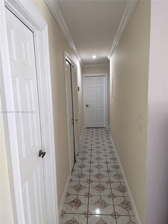 Hallway featuring tile flooring, crown molding, recessed lighting, and six-panel interior doors