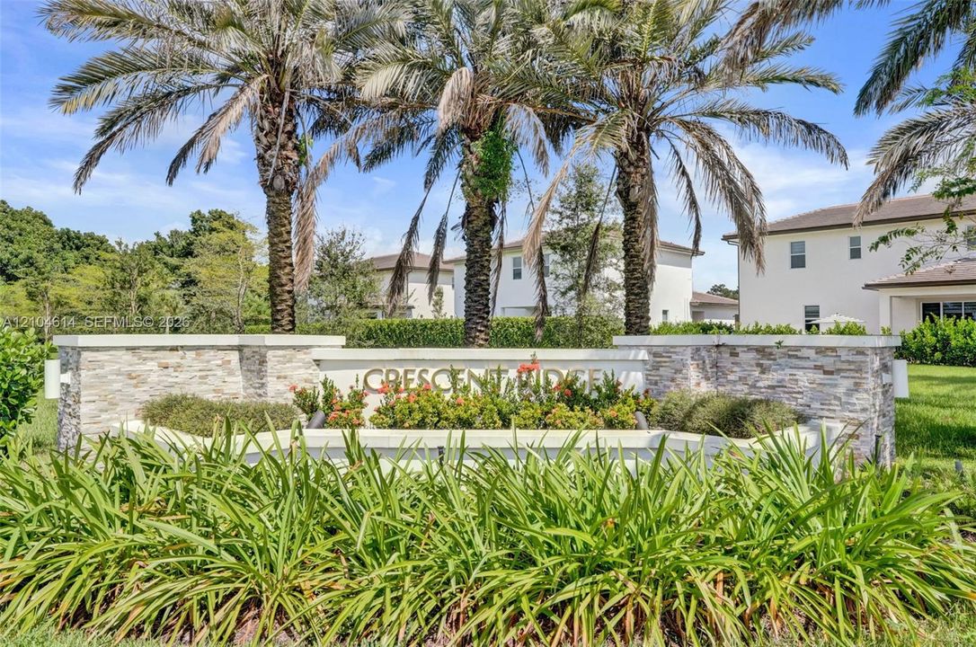 Stone-clad entry monument with integrated landscaping and mature palm trees