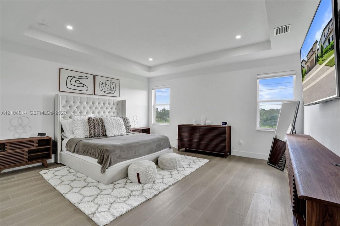 Tray ceiling with recessed lighting, wood look flooring, and multiple windows