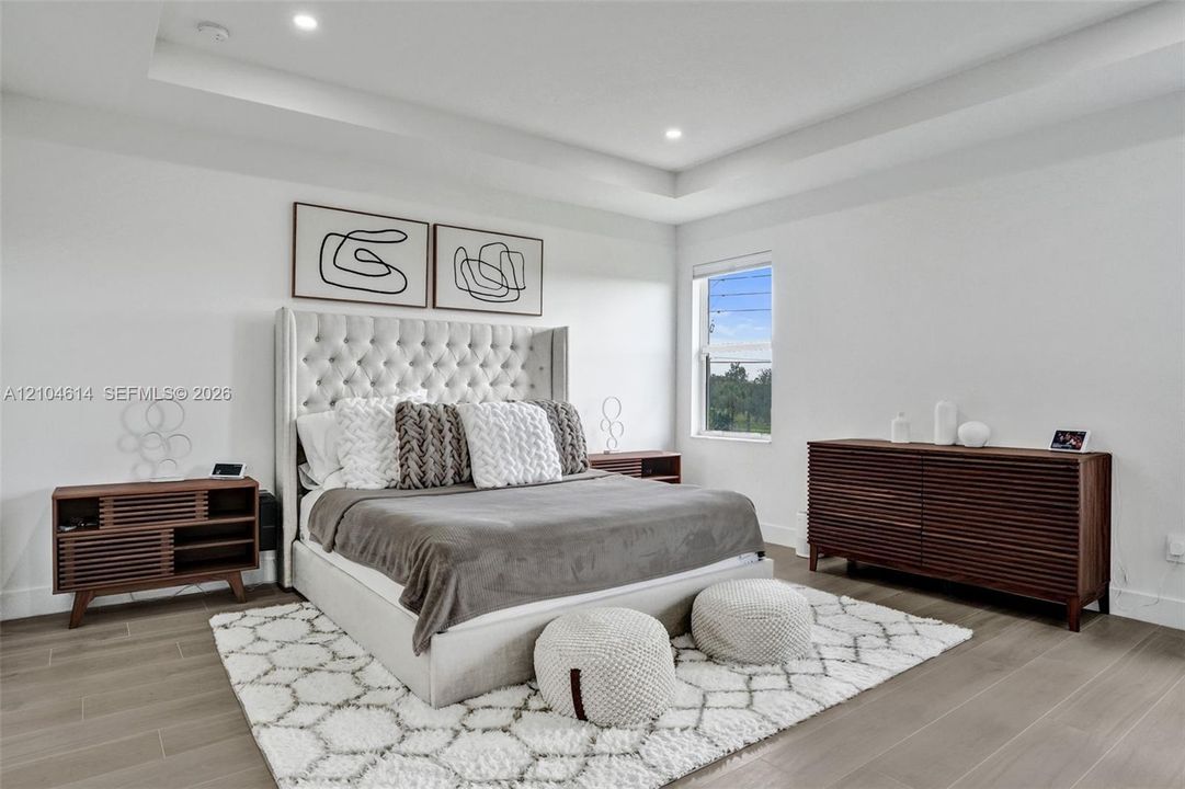Recessed lighting, tray ceiling, and light wood look flooring