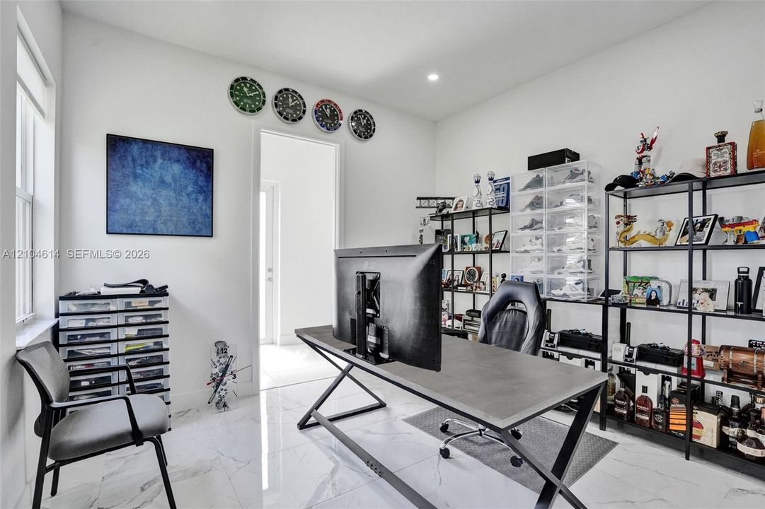 Recessed lighting, marble look flooring, white walls, and a large window
