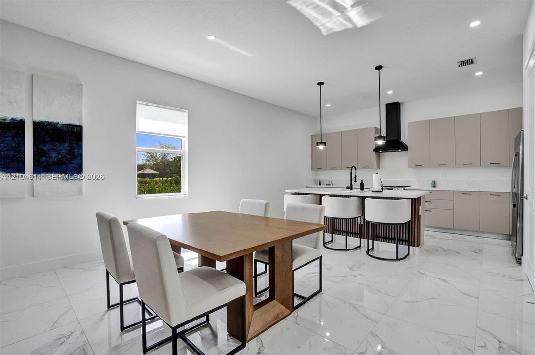 Open-concept living space featuring a modern kitchen with a large island, sleek cabinetry, and pendant lighting