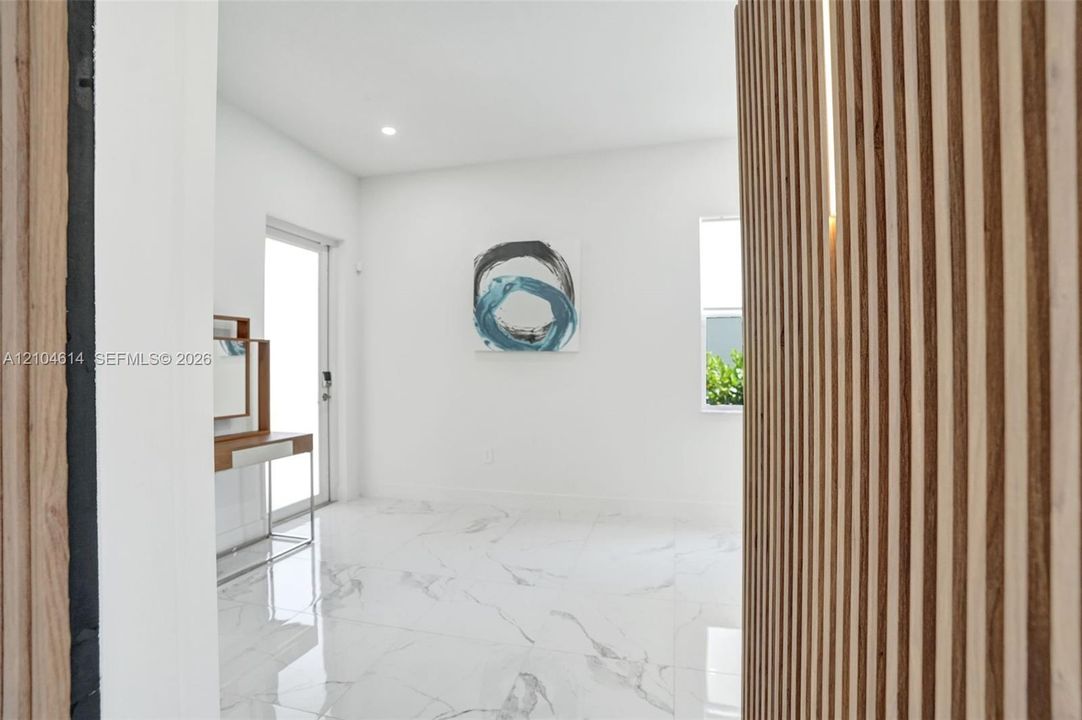 Wood slat wall paneling with integrated lighting, white walls, large format tile flooring, and a sliding glass door