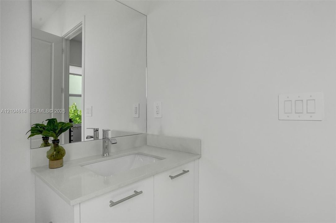 White vanity with an integrated rectangular sink, chrome faucet, and full-width mirror