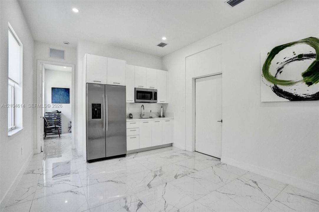 Kitchenette featuring stainless steel appliances, white cabinetry, undermount sink, and recessed lighting