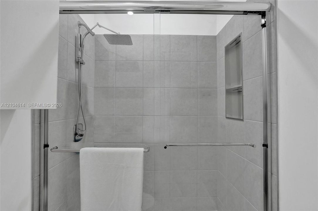 Frameless glass shower enclosure featuring a rectangular rain showerhead and a built-in shower niche