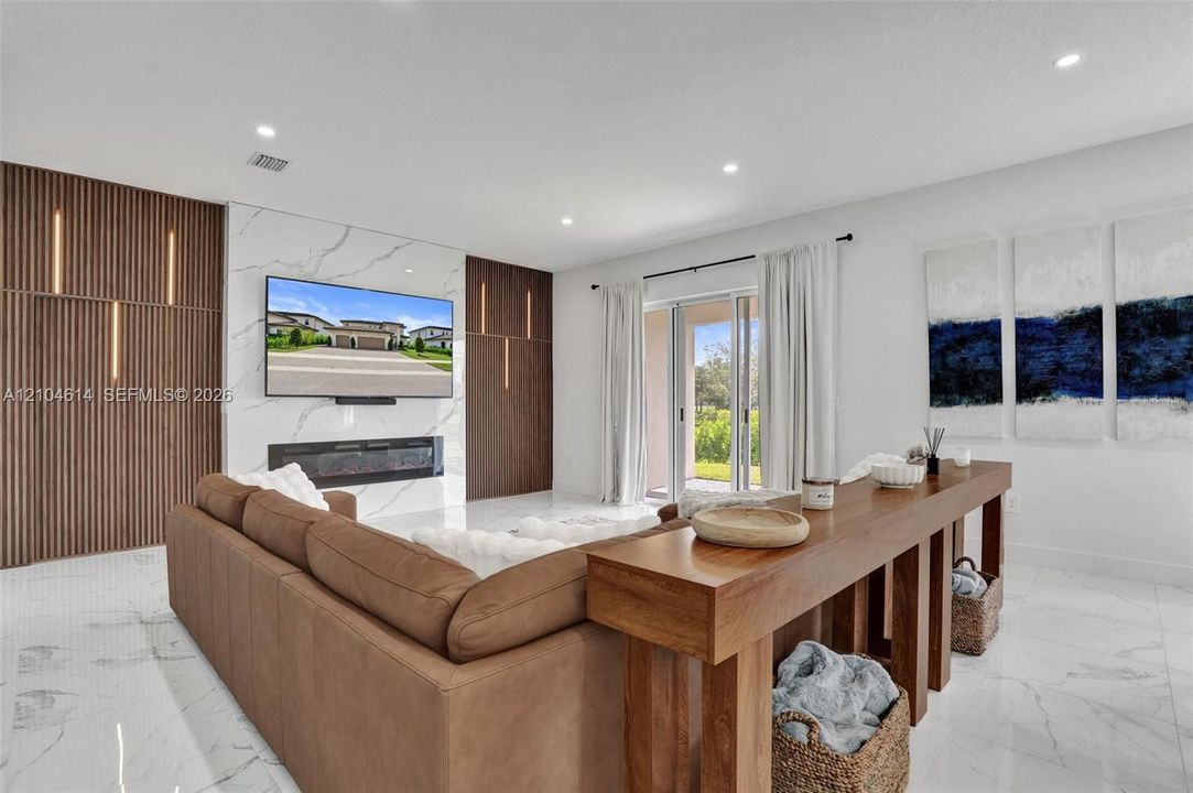 Spacious living area featuring large format floor tiling, a decorative electric fireplace, and a striking accent wall with integrated vertical lighting