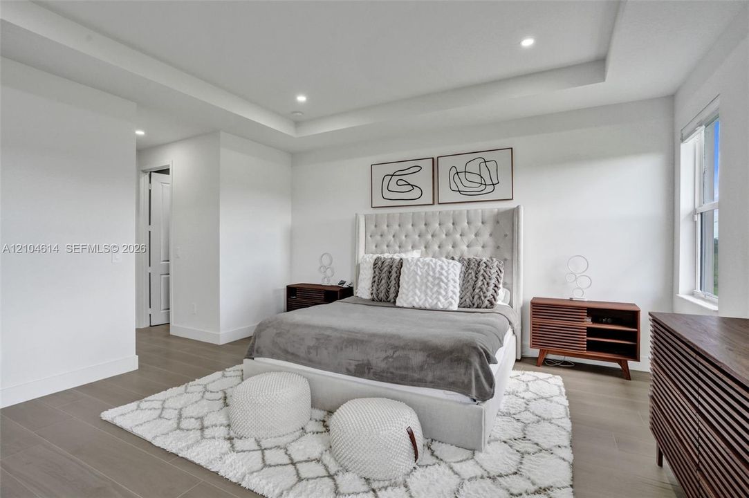 Tray ceiling with recessed lighting, wood look flooring, and a large window
