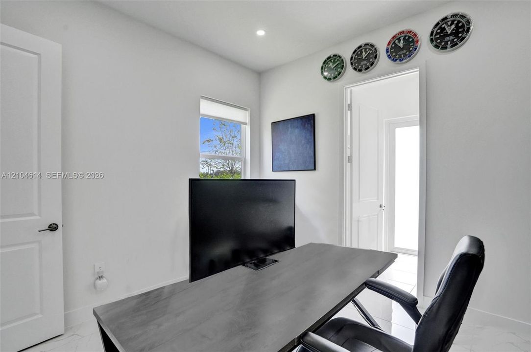 White interior walls, recessed ceiling lighting, light-toned flooring, and a white interior door with dark hardware
