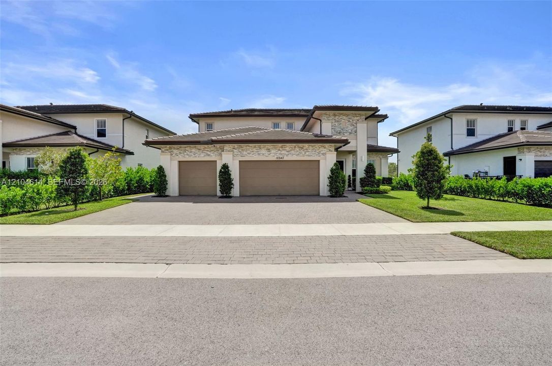 Contemporary stucco and stone-clad exterior with a two-car garage and a paved driveway