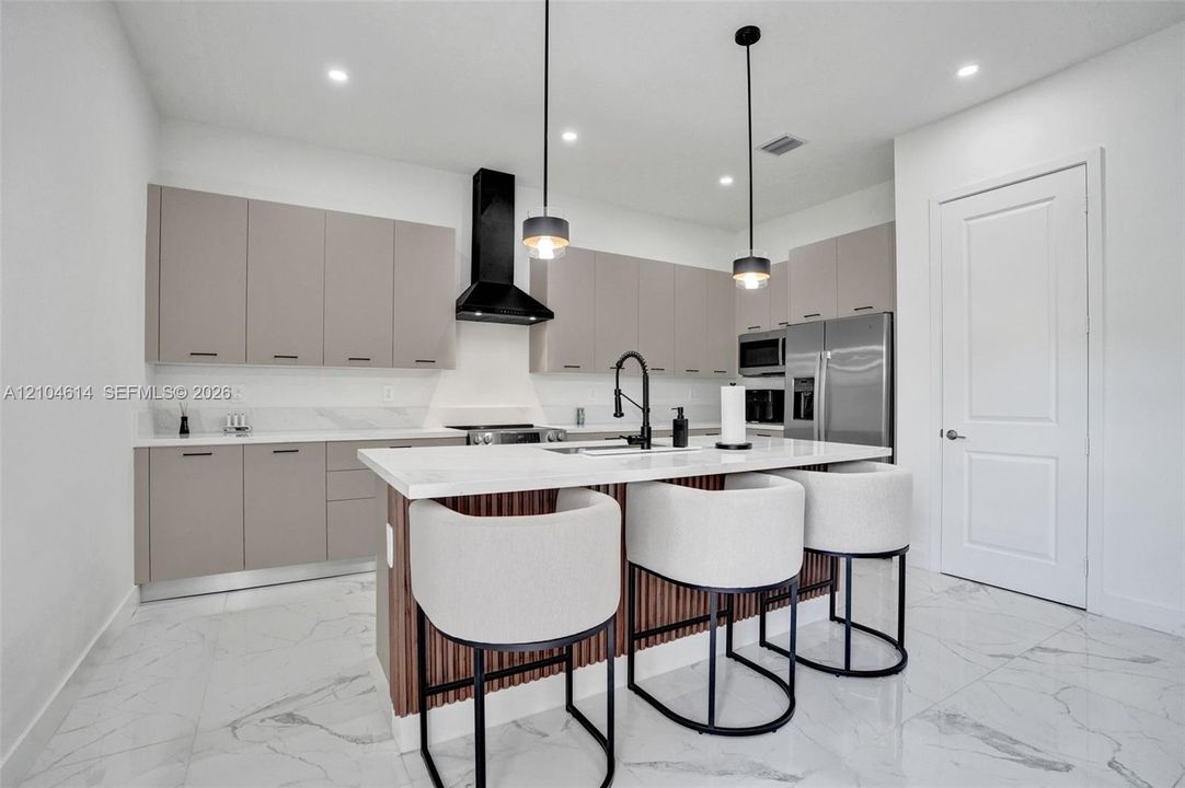 Kitchen featuring an island with white countertop, matte black faucet, and pendant lighting