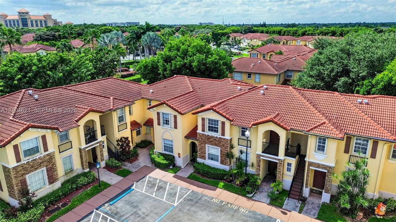 Multi-story building featuring stucco exterior walls, stone veneer accents, multi-gabled clay tile roof, and private covered entryways