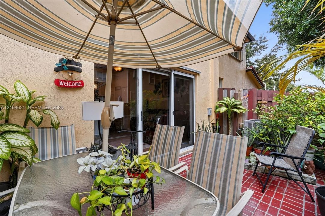 Outdoor patio featuring red tile flooring, stucco exterior wall, and sliding glass doors