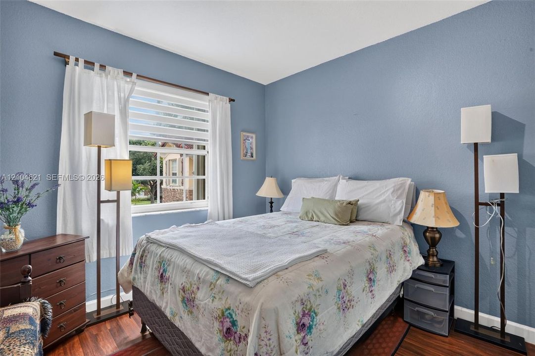 Room featuring wood-finish flooring, textured walls, and a multi-pane window with horizontal blinds