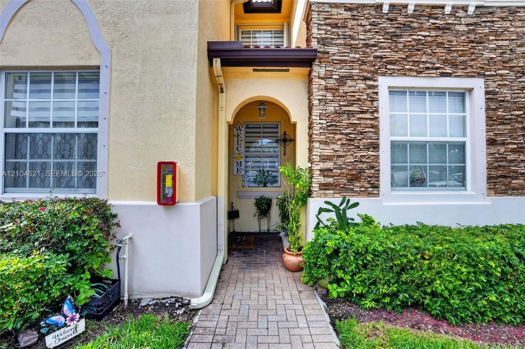 Exterior facade featuring textured stone masonry, stucco finish, arched entryway, and a paved brick walkway