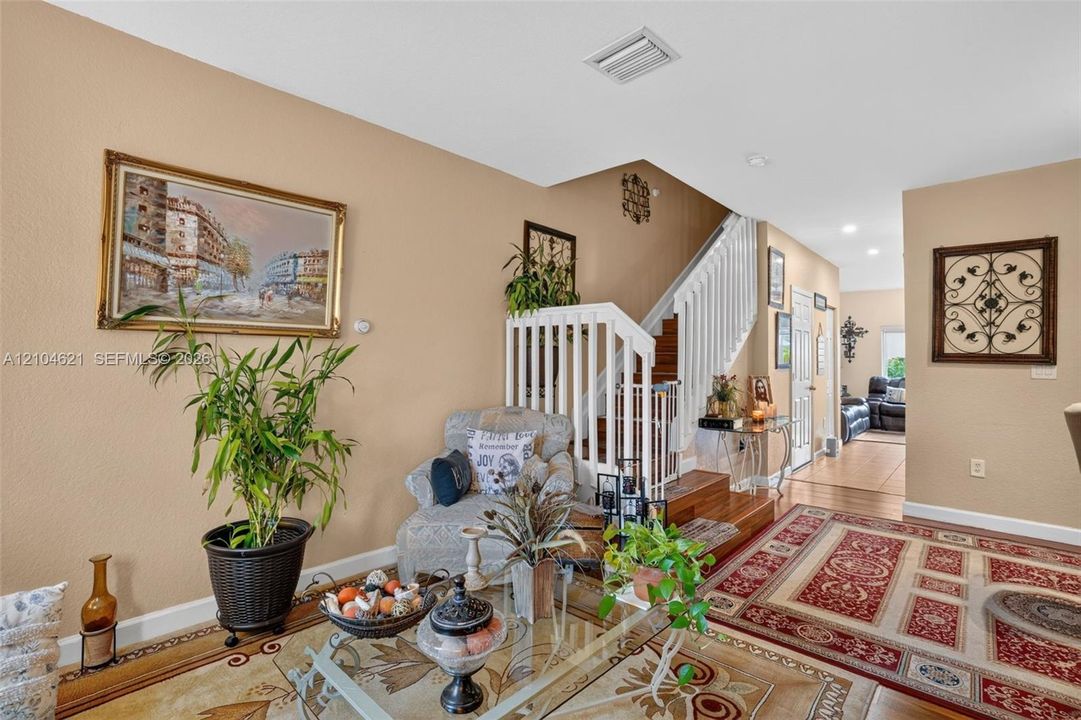 Interior space featuring wood-finish staircase with white balusters and railings, recessed ceiling lighting, and solid surface flooring