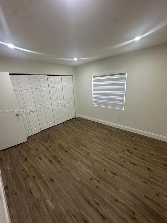 Wood-finish flooring, recessed lighting, horizontal window blinds, and bi-fold closet doors