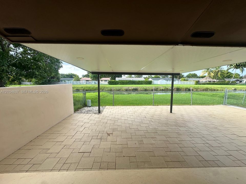 Covered patio with integrated lighting, paver flooring, and a low wall