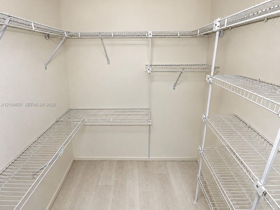 Walk-in storage space featuring wood-finish flooring and multi-level white wire shelving