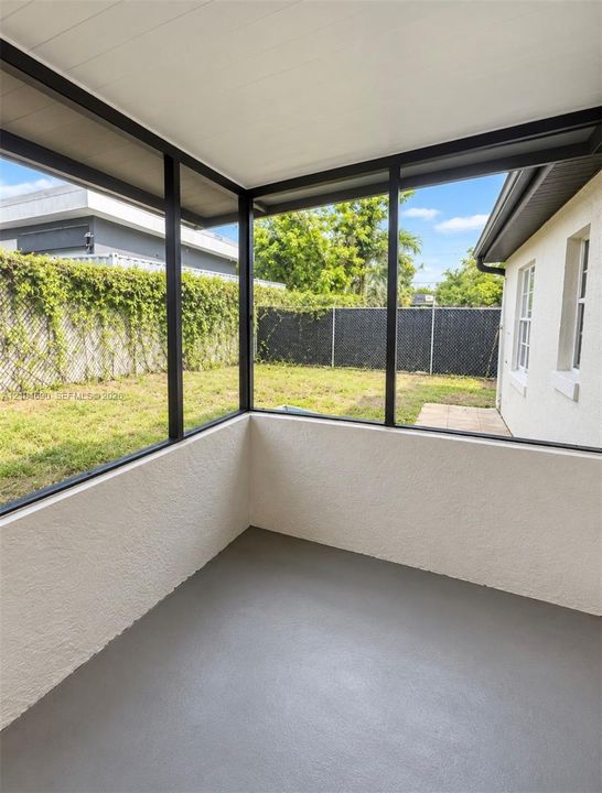 Screened-in porch featuring a painted concrete floor, textured wall finishes, and a dark-framed enclosure