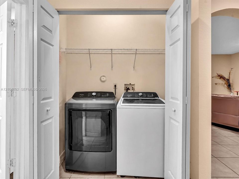 Laundry area featuring bi-fold doors, white ceramic tile flooring, and integrated wire shelving