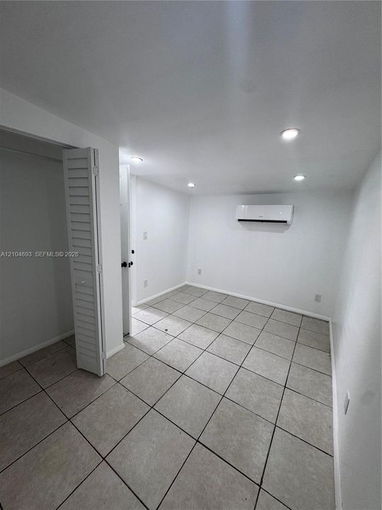 Recessed lighting, tile flooring, louvered bi-fold closet doors, wall-mounted air conditioning unit
