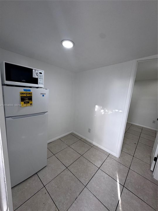 Recessed ceiling lighting illuminates the space, featuring white walls and square tile flooring