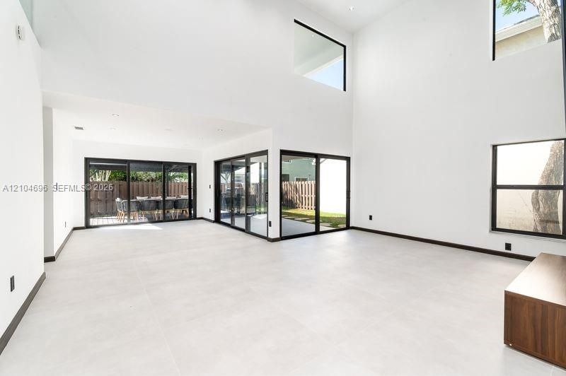 Double-height ceilings, large-format tile flooring, recessed lighting, and expansive glass sliding doors with black frames